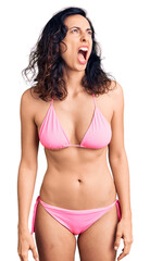 Obraz premium Young beautiful hispanic woman wearing bikini angry and mad screaming frustrated and furious, shouting with anger. rage and aggressive concept.