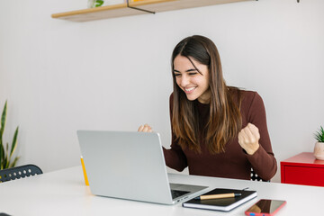 Excited young adult businesswoman feeling happy after receiving good news on email.