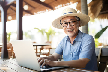 senior Asian man working remotely on laptop on summer vacation - happiness digital nomad remote work business lifestyle concept - obrazy, fototapety, plakaty