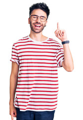 Young hispanic man wearing casual clothes showing and pointing up with finger number one while smiling confident and happy.