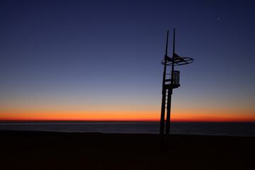 Fototapeta premium Dawn on a Mediterranean beach with the silhouette of the lifeguard tower