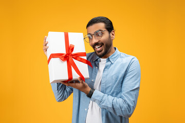 Happy millennial indian man with beard and glasses sharing idea for present, show gift
