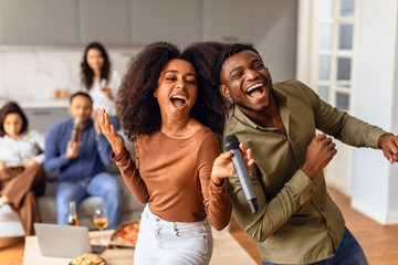 black couple with diverse friends singing and celebrating together indoor
