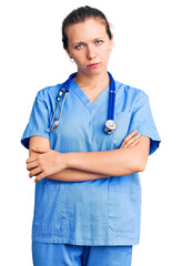 Young beautiful blonde woman wearing doctor uniform and stethoscope skeptic and nervous, disapproving expression on face with crossed arms. negative person.