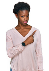 Young african american girl wearing casual clothes pointing with hand finger to the side showing advertisement, serious and calm face