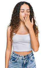 Teenager hispanic girl wearing casual clothes bored yawning tired covering mouth with hand....