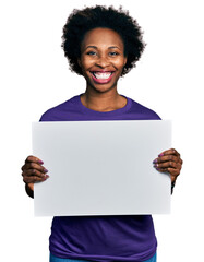 African american woman with afro hair holding blank empty banner smiling with a happy and cool...