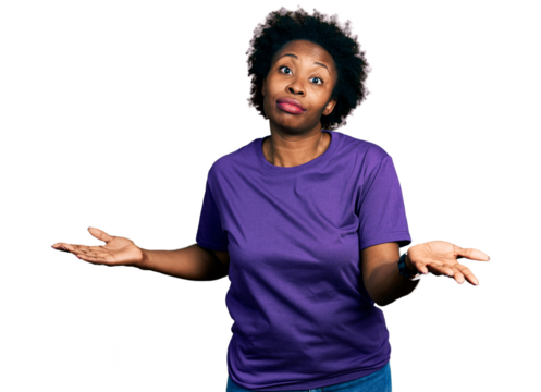 African american woman with afro hair wearing casual purple t shirt clueless and confused expression with arms and hands raised. doubt concept.