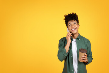 Happy young african american man talking on phone, drinking coffee