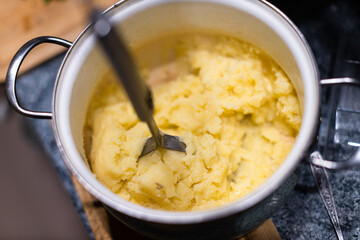 Mashing potatoes with a hand in a pot - sometimes called smashed potatoes