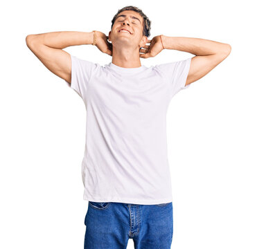 Young handsome man wearing casual white tshirt relaxing and stretching, arms and hands behind head and neck smiling happy