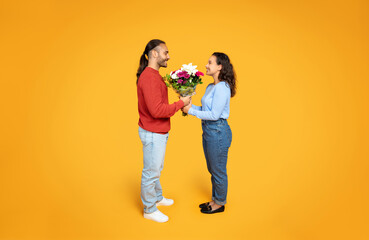 A smiling man gives a lush bouquet to a woman