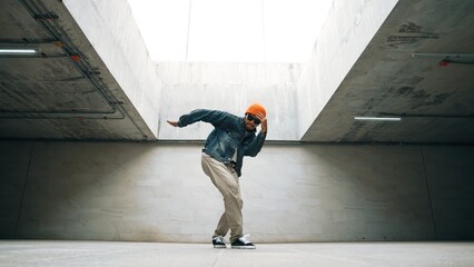 Stylish happy hipster perform break dance or freestyle foot step in building. Professional break dancer practice b-boy dance while wear stylish cloth. Modern lifestyle. Outdoor sport 2024. Sprightly.