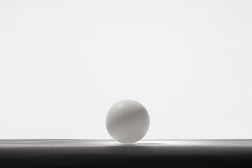 The hand picks a pingpong white ball in front of white background.