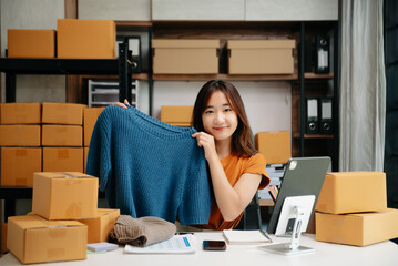 Asian lady blogger showing clothes in front of the camera to recording vlog video live streaming at...