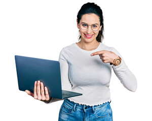 Young hispanic woman working using computer laptop smiling happy pointing with hand and finger
