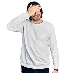 Middle age caucasian man wearing casual clothes covering eyes with hand, looking serious and sad. sightless, hiding and rejection concept