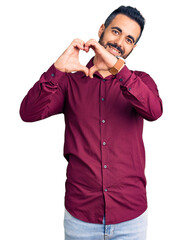 Young hispanic man wearing casual clothes smiling in love showing heart symbol and shape with hands. romantic concept.