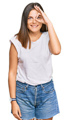 Obraz premium Young caucasian woman wearing casual white tshirt doing ok gesture with hand smiling, eye looking through fingers with happy face.