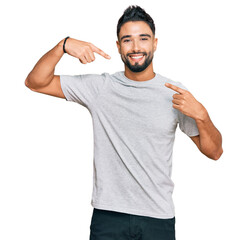 Young man with beard wearing casual grey tshirt smiling cheerful showing and pointing with fingers teeth and mouth. dental health concept.