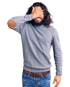 Young arab man wearing casual clothes smiling and laughing with hand on face covering eyes for surprise. blind concept.