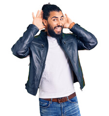 Young arab man wearing casual leather jacket smiling cheerful playing peek a boo with hands showing...