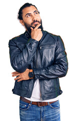 Fototapeta premium Young arab man wearing casual leather jacket with hand on chin thinking about question, pensive expression. smiling with thoughtful face. doubt concept.