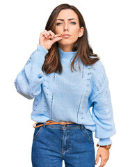 Young brunette woman wearing casual winter sweater mouth and lips shut as zip with fingers. secret...