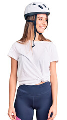 Young beautiful girl wearing bike helmet looking away to side with smile on face, natural expression. laughing confident.