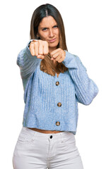Young woman wearing casual clothes punching fist to fight, aggressive and angry attack, threat and...
