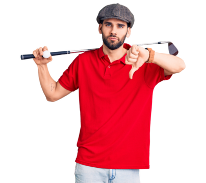 Young handsome man with beard playing golf holding club and ball with angry face, negative sign showing dislike with thumbs down, rejection concept
