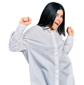 Young brunette woman with blue eyes wearing oversize white shirt dancing happy and cheerful, smiling moving casual and confident listening to music
