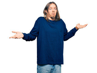 Handsome caucasian man with long hair wearing casual winter sweater clueless and confused...