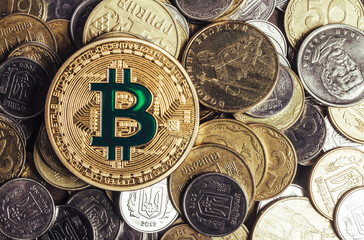Photo of golden bitcoin coin laying on Ukrainian pile of coins.