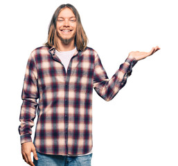 Handsome caucasian man with long hair wearing hipster shirt smiling cheerful presenting and pointing with palm of hand looking at the camera.