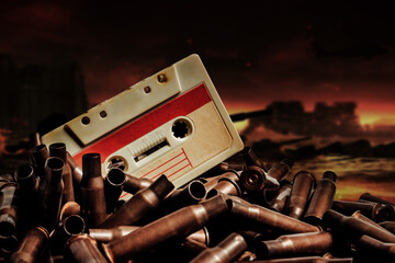 Photo of an old audio tape cassette on pile of bullets. Ruined city battlefield or wasteland...