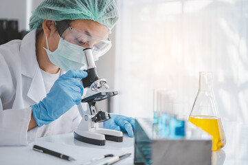 female medical researcher looking at a microscope in a medical laboratory. Medical experimental...