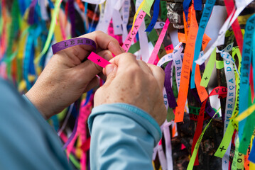 Tourist hands tying souvenir ribbon on the iron railing of the Senhor do Bonfim church in the city...