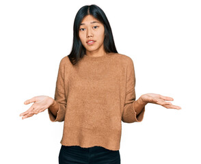 Beautiful young asian woman wearing casual winter sweater clueless and confused expression with...