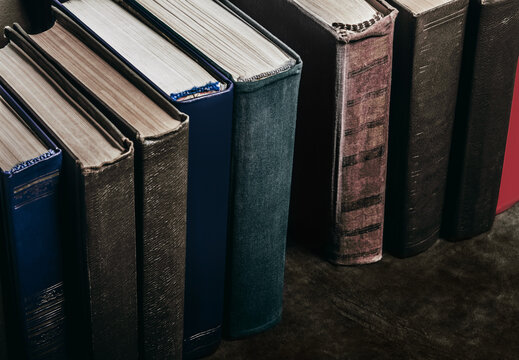 Photo of old antique books row standing on leather surface table.