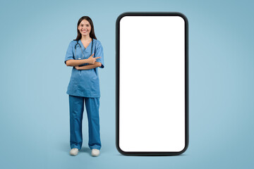 Young caucasian nurse by large phone screen, blue background
