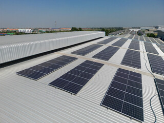 Top aerial view of solar roof system at the rooftop of factory warehouse. renewable energy of photovoltaic for reduce energy and carbon footprint. clean energy. solar panel and structure at building.