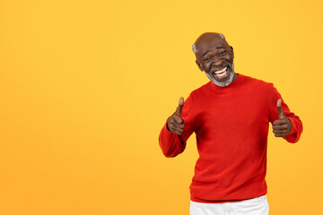 Exultant senior Black man with a radiant smile giving two thumbs up, wearing a festive red sweater