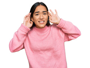 Young asian woman wearing casual winter sweater trying to hear both hands on ear gesture, curious for gossip. hearing problem, deaf