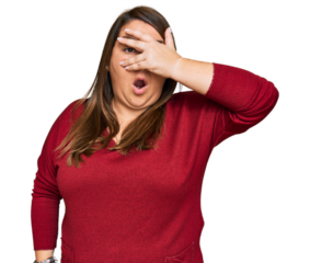 Beautiful brunette plus size woman wearing casual clothes peeking in shock covering face and eyes with hand, looking through fingers with embarrassed expression.