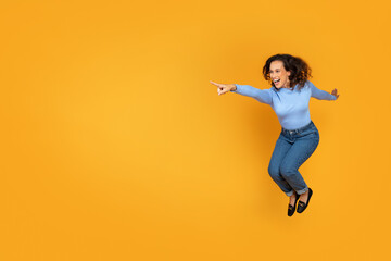 Cheerful excited young woman jumping on yellow, copy space