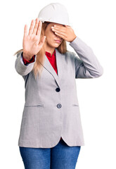 Beautiful young woman wearing architect hardhat covering eyes with hands and doing stop gesture with sad and fear expression. embarrassed and negative concept.