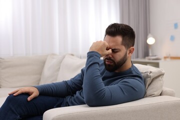 Fototapeta premium Man suffering from headache on sofa at home