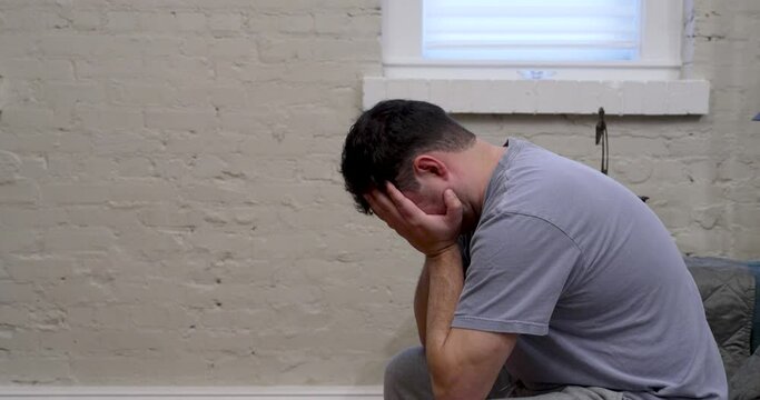 Young adult male frustrated or depressed with both hands covering his face.  