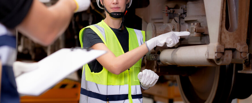 Young caucasian engineer man and woman or worker checking electric train for planning maintenance looking document on clipboard in station, transport and infrastructure, inspector check transport.